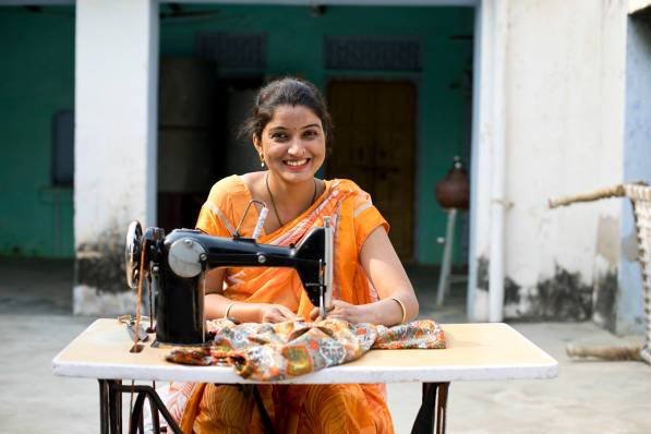 Happy Indian woman sewing clothes with sewing machine